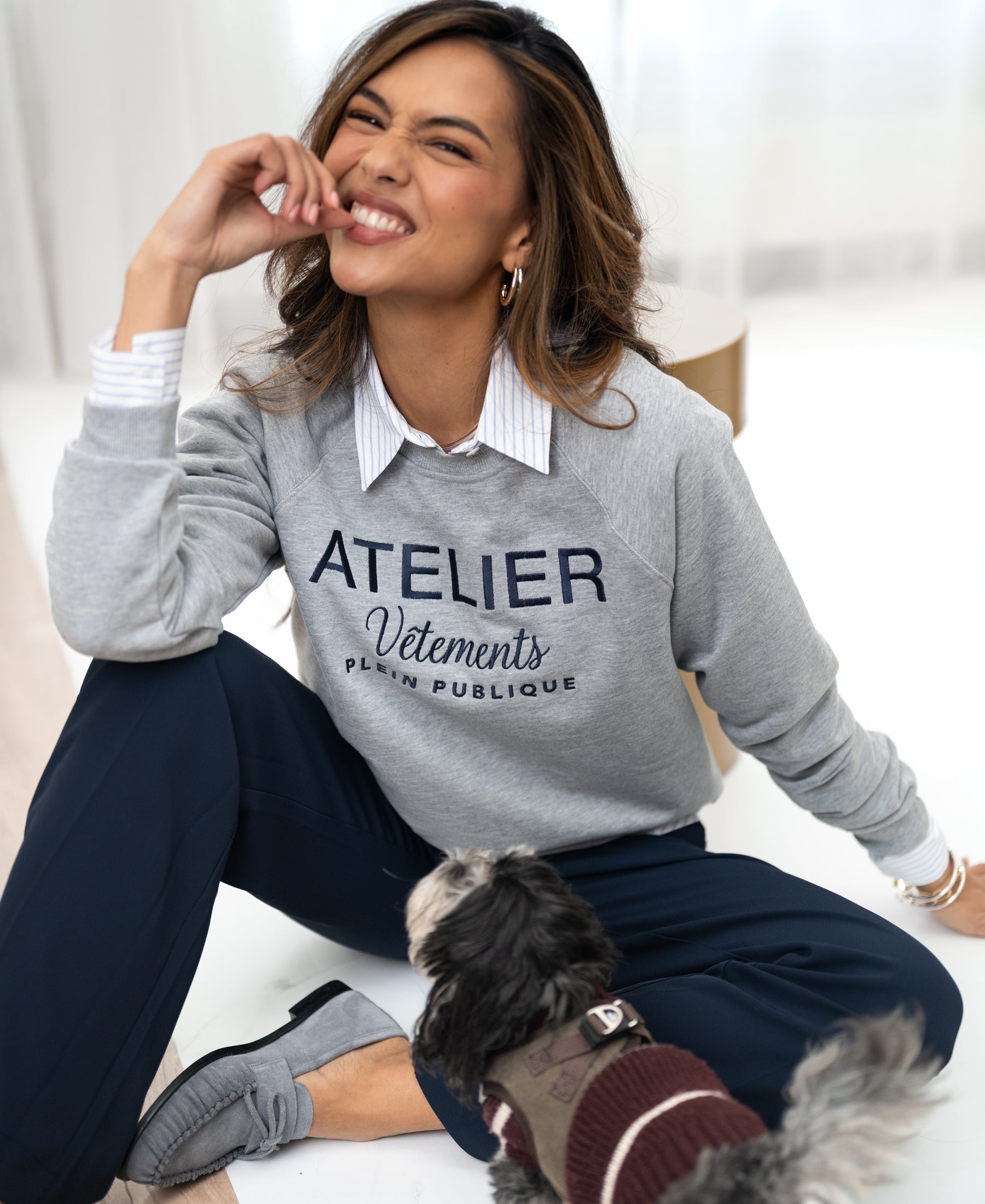 Woman smiling in a light grey LA HARPER sweater by PLEIN PUBLIQUE.