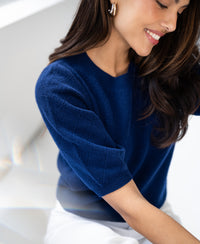 Navy argyle merino wool sweater shown indoors in soft natural light.