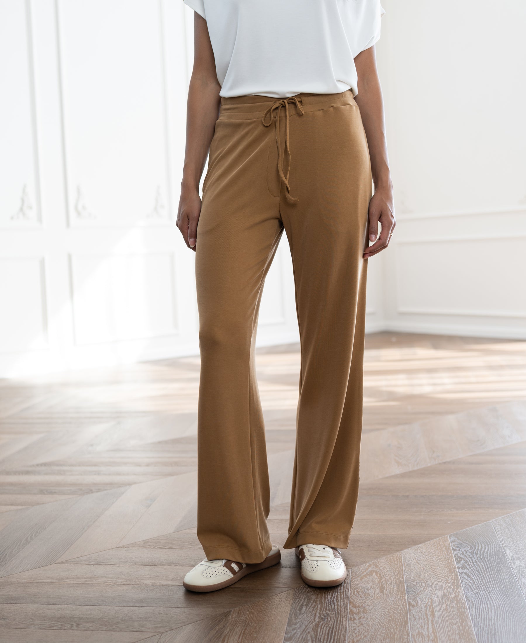 Light camel lounge pants shown in a bright room.