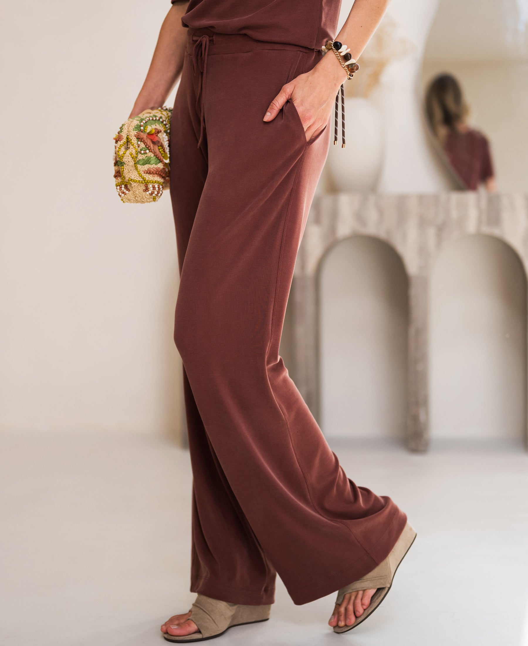 Person wears the LE HUGO Henna lounge pants by PLEIN PUBLIQUE in a modern, minimal room.