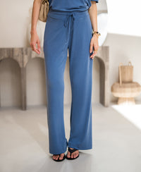 Blue PLEIN PUBLIQUE LE HUGO lounge pants, shown indoors against neutral furniture.