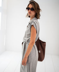 Woman wearing a grey mélange travel polo dress in a bright, minimalist room.