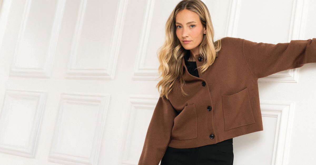 Brown button-up cardigan displayed against a white paneled wall.