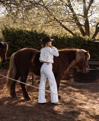 White wide leg jeans from PLEIN PUBLIQUE shown outdoors on a sunny day.