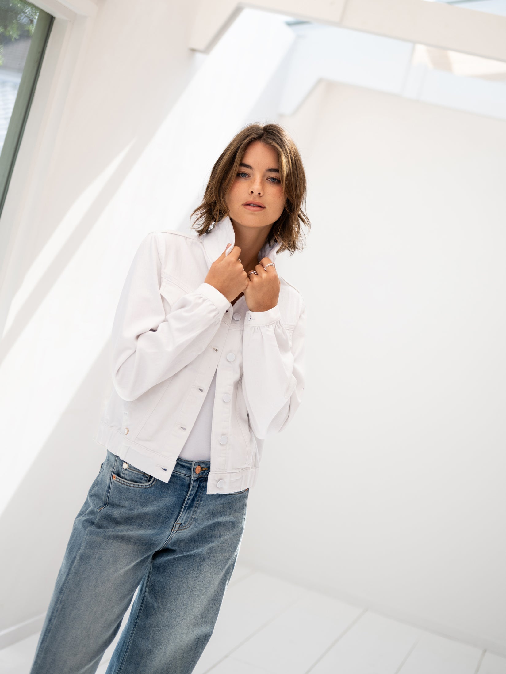 White and blue denim jacket in a bright, minimalist room.