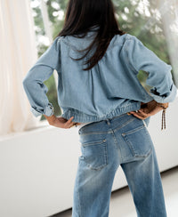 Wide leg jeans in light stone color, shown from the back with hands on hips.