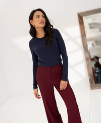 Woman wearing a Luxe long sleeve T-shirt LA JANE in navy by PLEIN PUBLIQUE stands near a large indoor mirror.