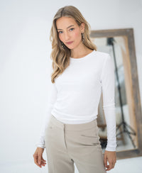 Woman wearing the PLEIN PUBLIQUE Luxe long sleeve LA JANE white T-shirt, standing before a mirror.