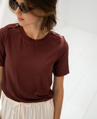 Woman wearing bamboo T-shirt in red-brown from PLEIN PUBLIQUE in a bright room.