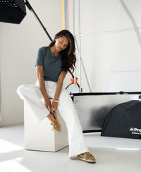 A woman in a relaxed fit bamboo T-shirt in light green sits, looking down.