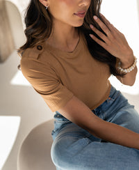 Woman wearing a bamboo T-shirt in garden yellow by PLEIN PUBLIQUE, shown in soft light.