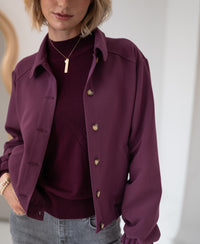 Woman wearing a Bordeaux turtleneck sweater by PLEIN PUBLIQUE indoors.