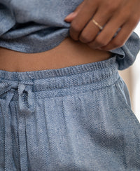 Close-up of a hand holding up loose-fitting satin wide-leg summer pants with a jeans print.