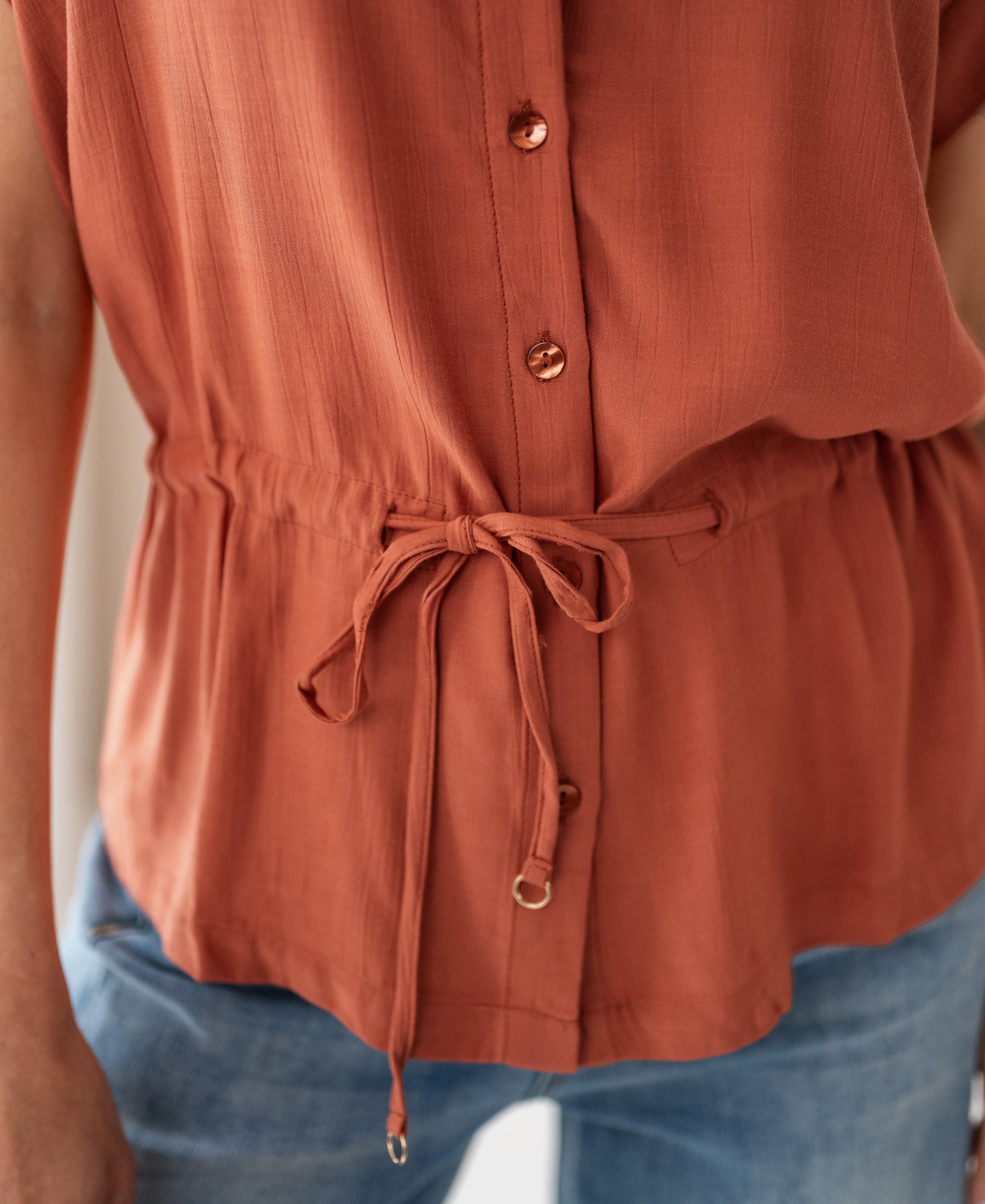 Rust viscose blouse with buttons and waist detail.