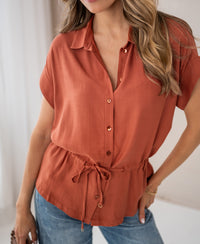 Terra-colored LA JODY blouse by OVERIG, worn by a woman, shown indoors.