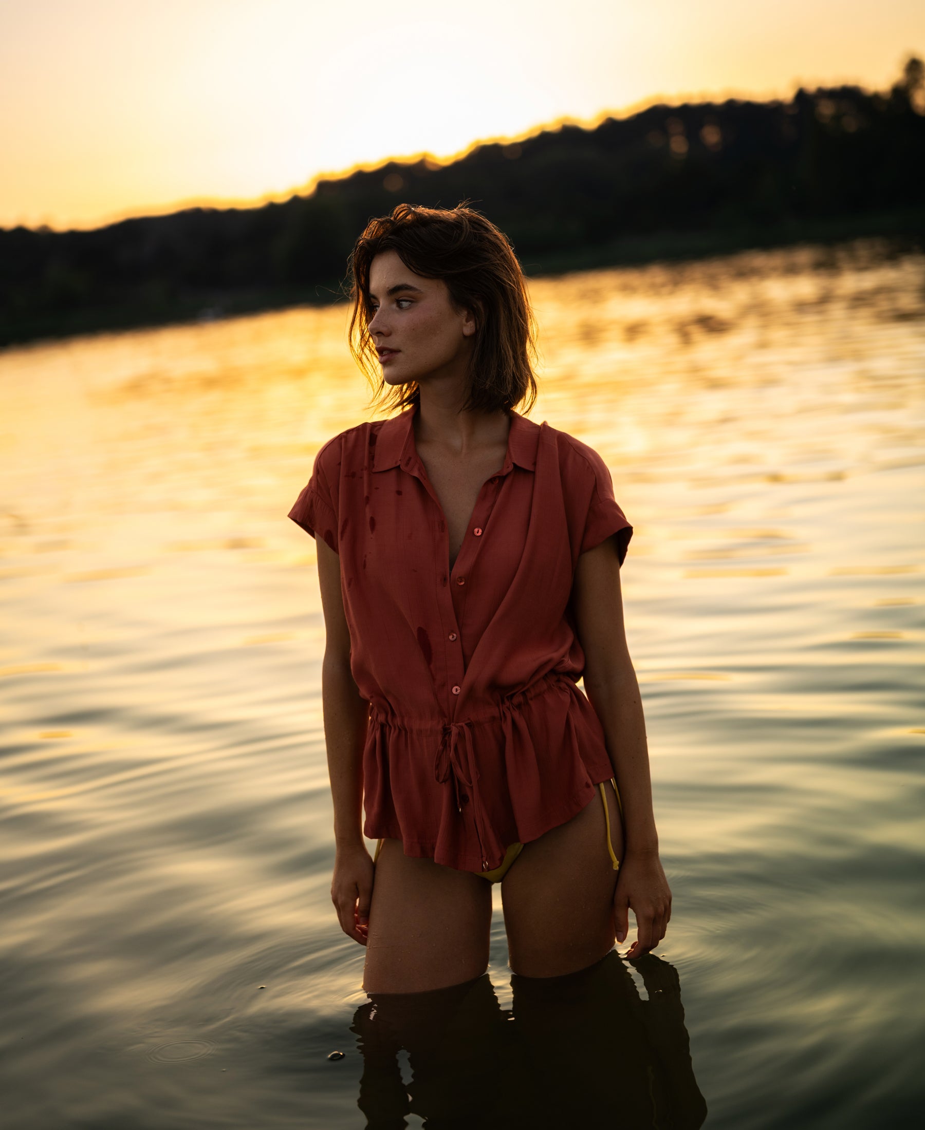 Woman in lake at sunset, wearing the Terra-colored LA JODY blouse, water thigh-high.