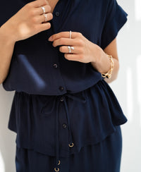 Woman wearing a dark blue LA JODY blouse, adjusting the waist tie.