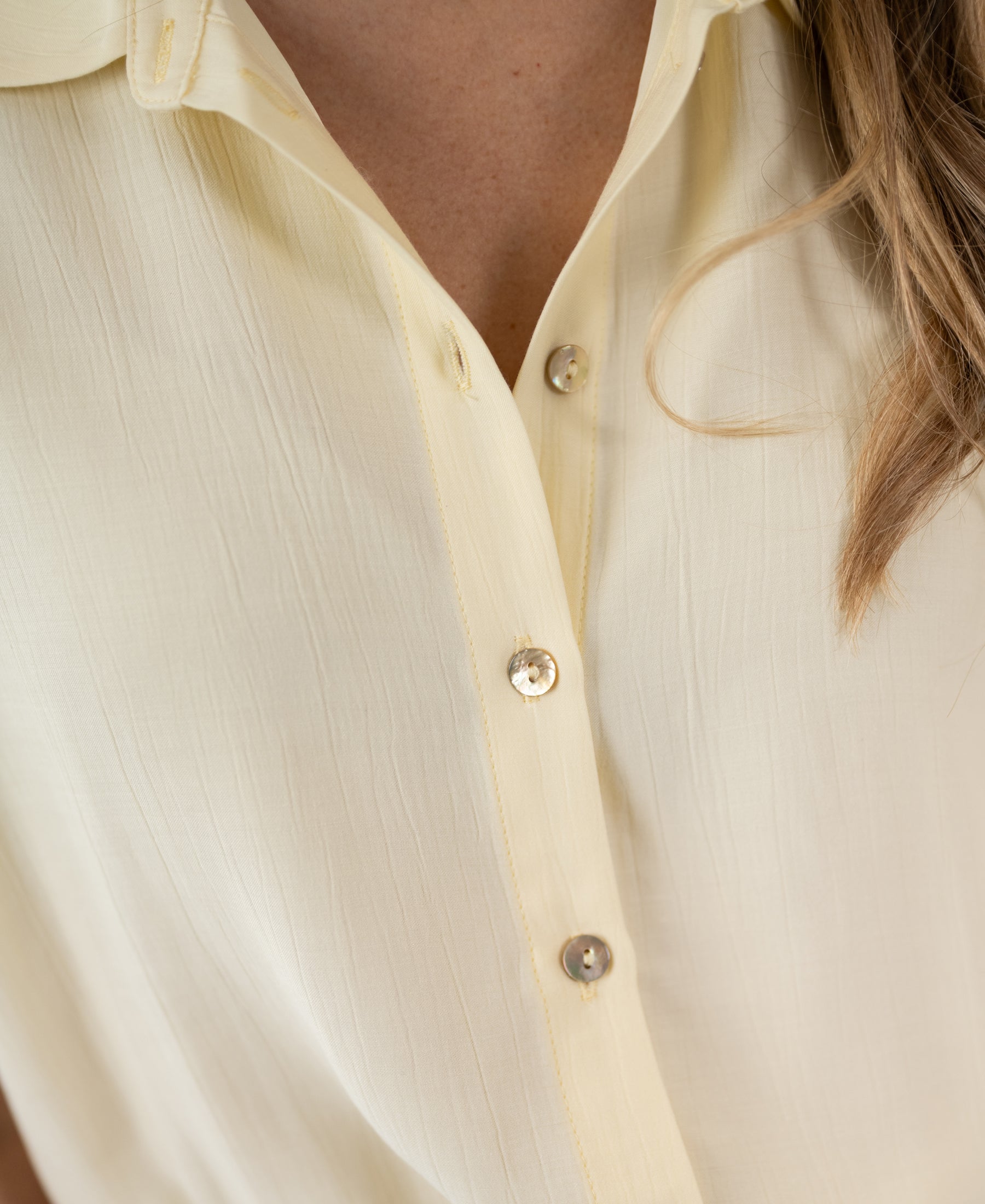 Close-up of soft yellow LA JODY blouse, partly unbuttoned.