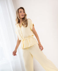 Loose, soft yellow LA JODY blouse shown from the side on a woman standing by a window, smiling.