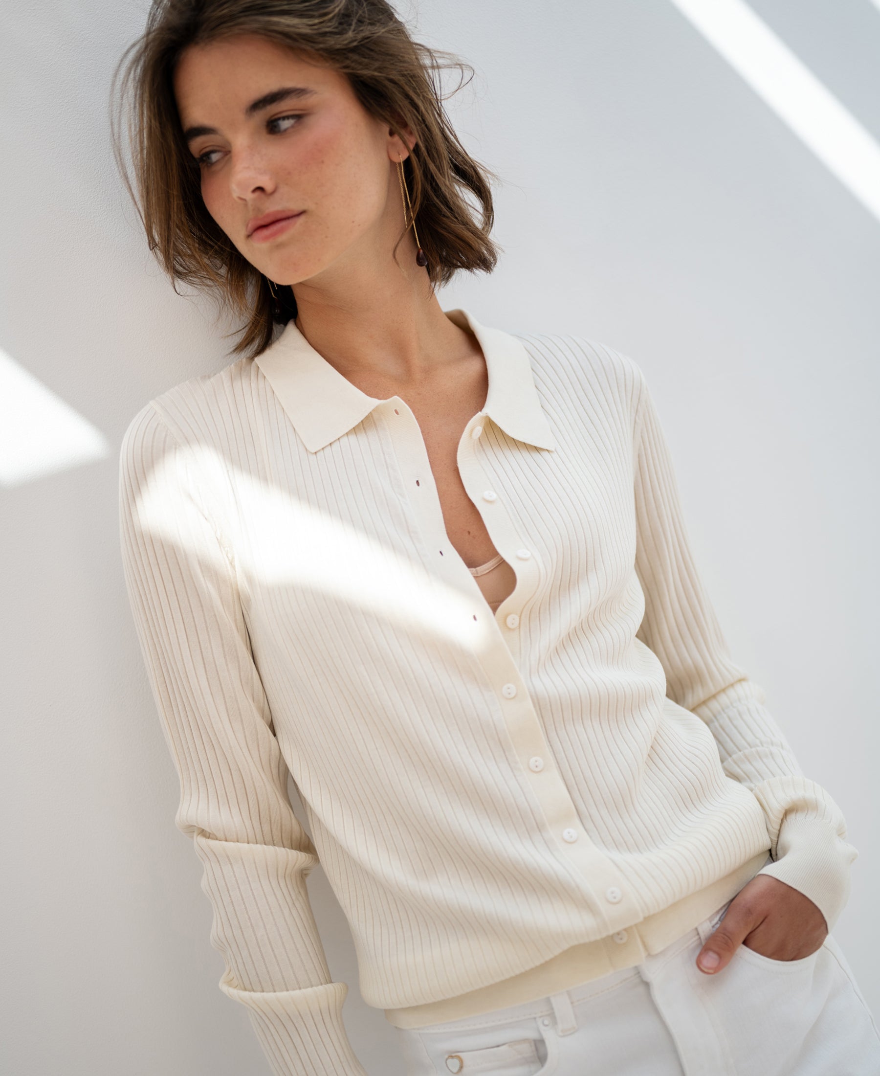 Cream ribbed cardigan in Tencel-silk, shown from the front against a white wall.