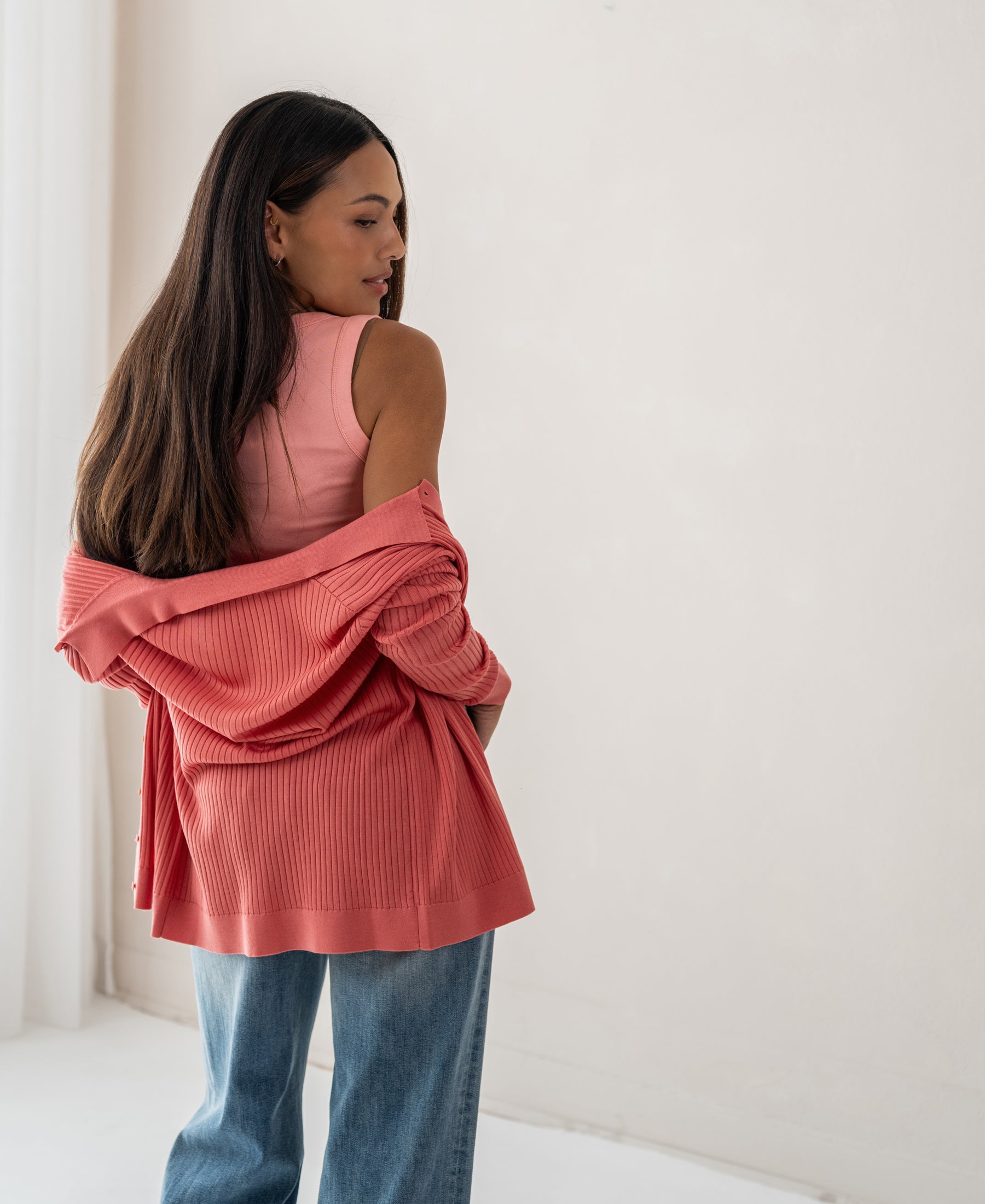 Woman wears pink Tencel-silk ribbed cardigan indoors.