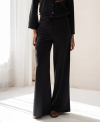 Woman wears black PLEIN PUBLIQUE LA JULIA travel pants indoors in natural sunlight; wrinkle-resistant quality.
