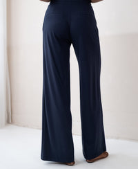 Womens travel pants in dark blue, loose fit with elastic waist, shown from the back.