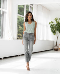Lyocell top in mist green shown indoors, with a bright room, large windows, and plants visible in the background.