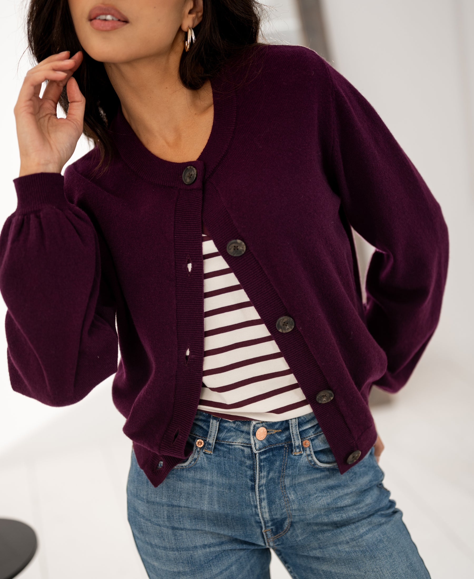 Woman wearing the PLEIN PUBLIQUE round neck vest in dark cassis, hand near face.