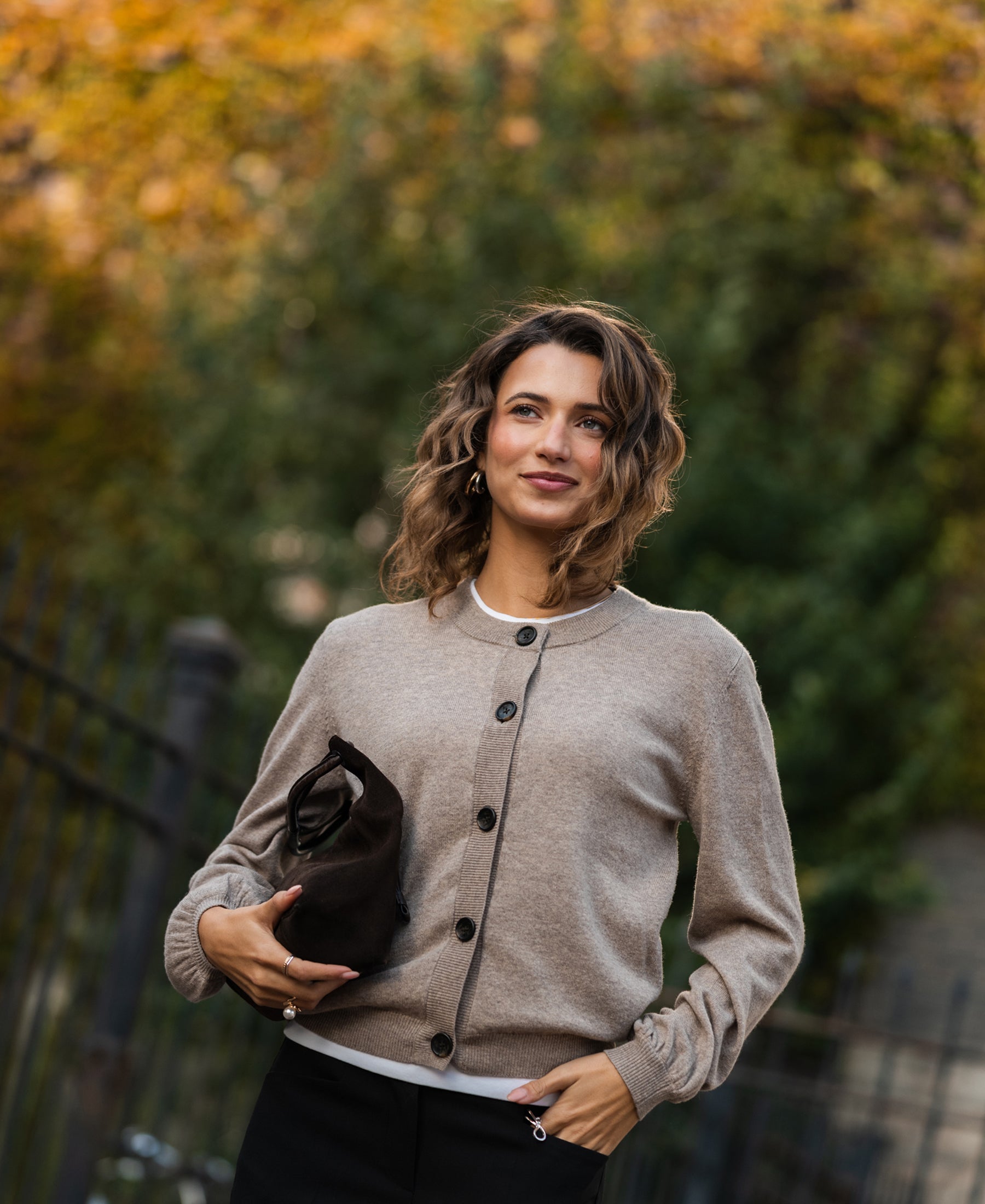 Woman wearing a warm taupe PLEIN PUBLIQUE round neck vest outdoors.