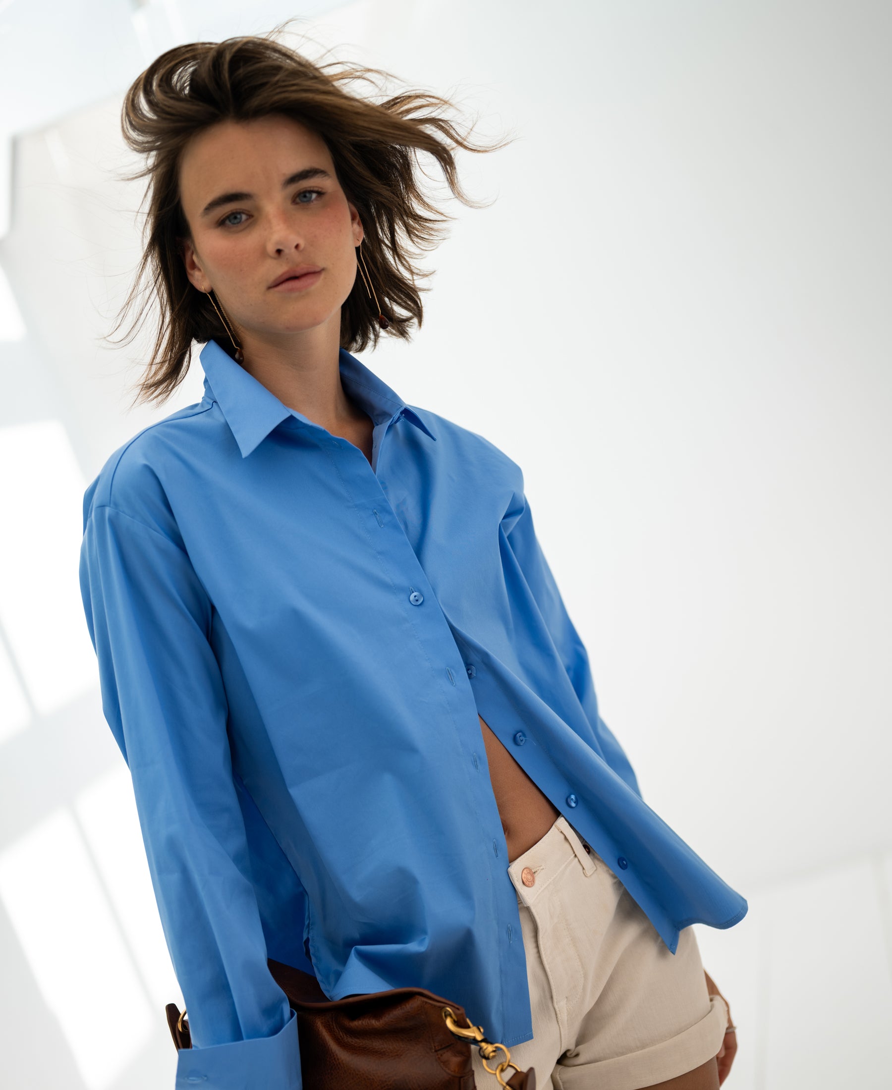 Blue oversized easy-iron blouse, shown indoors on a woman.