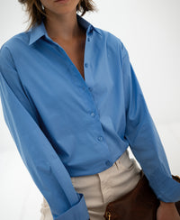 Back view of woman wearing PLEIN PUBLIQUEs blue oversized easy-iron blouse, LE LILLE.
