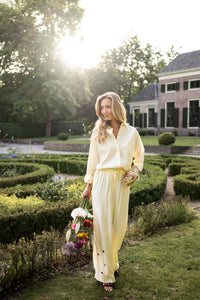 Oversized easy-iron blouse in soft yellow, shown outdoors.