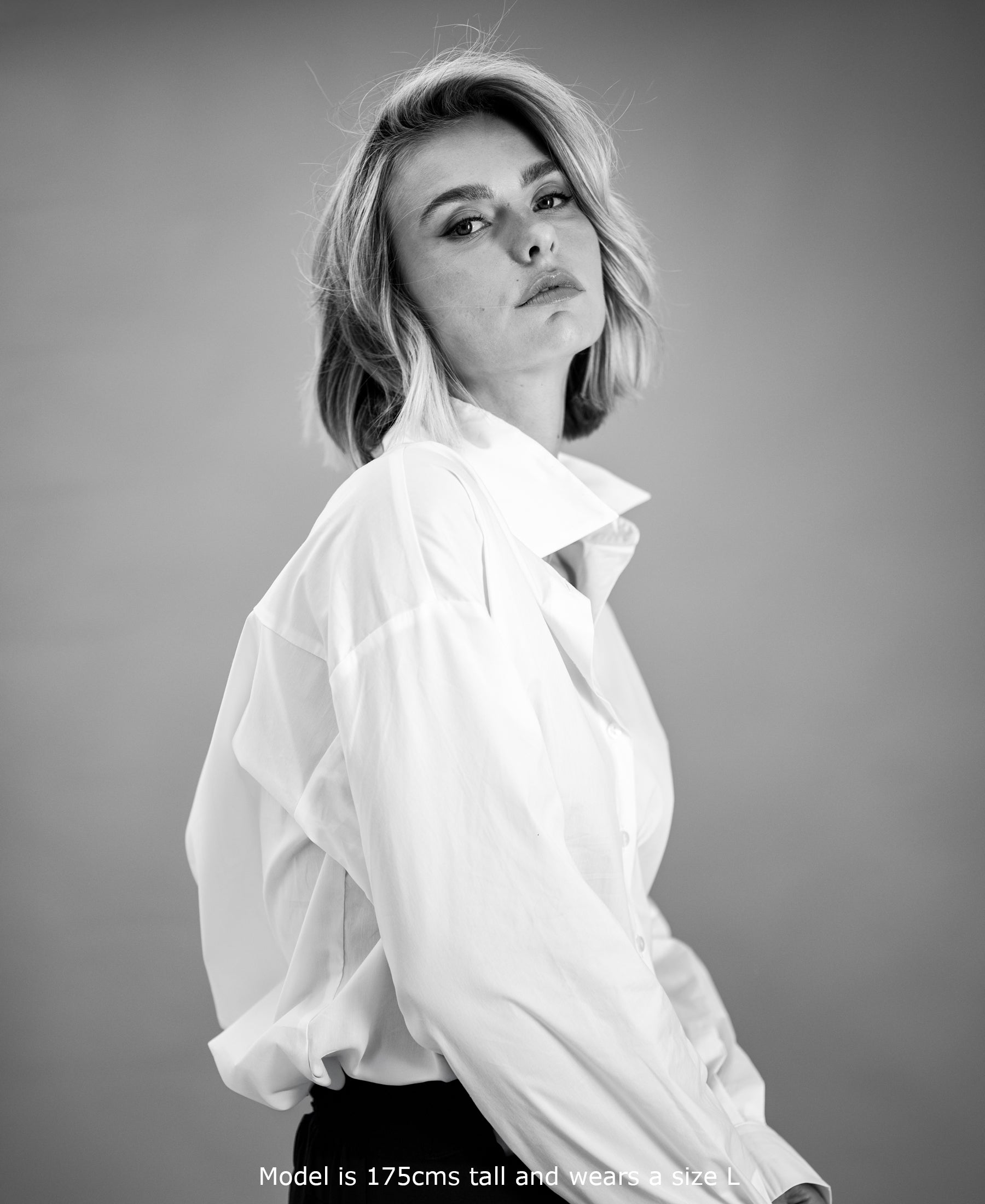 Black & white photo of oversized easy-iron white blouse; front view. Model’s height and size shown.
