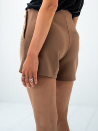 Side view of person wearing camel-gold buttoned shorts in stretch crêpe jersey.