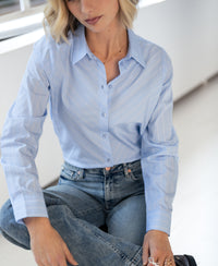 Striped blouse in light blue, white, and navy shown indoors.