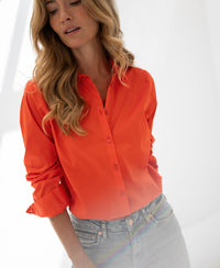 Woman wearing Plein Publique coral La Loire blouse in soft natural light.