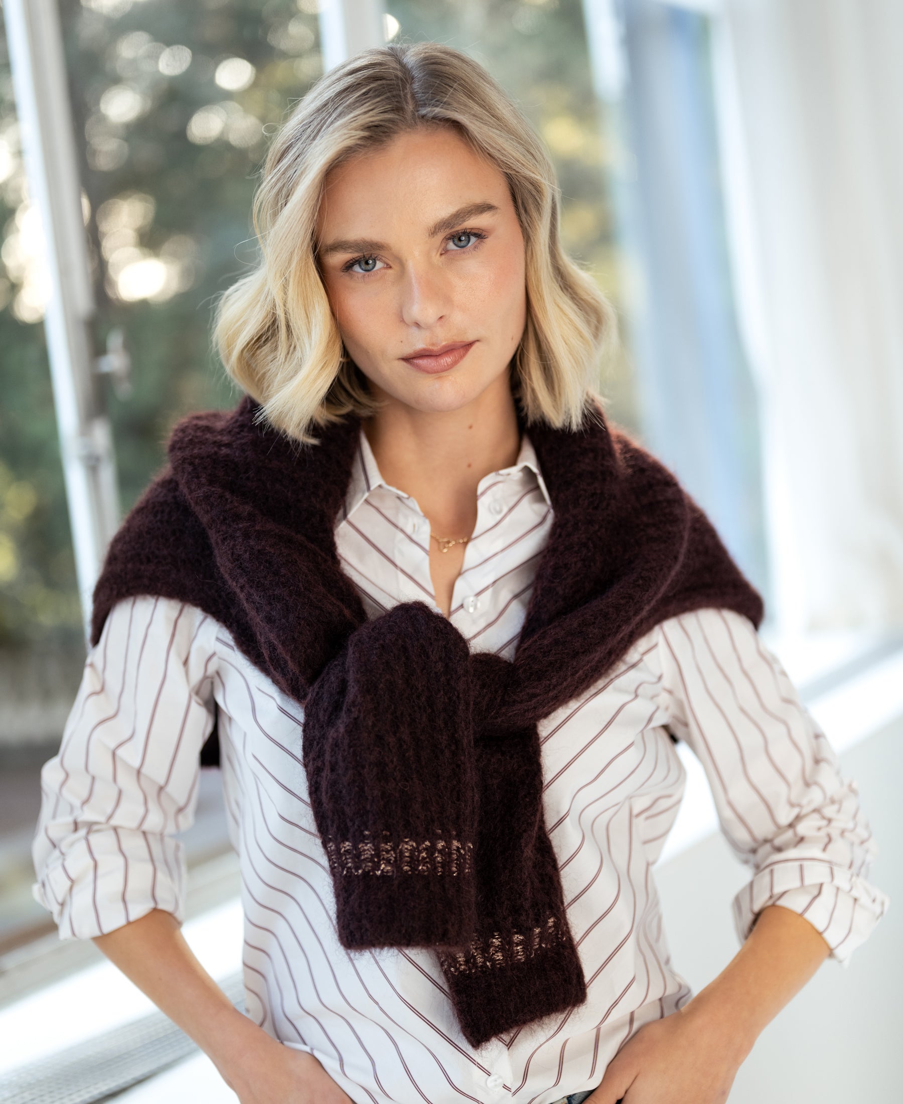 Striped blouse in ivory and wine red by PLEIN PUBLIQUE, shown indoors near a window.
