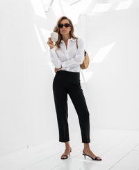 White LA LOIRE blouse by Plein Publique shown on model standing in bright room.