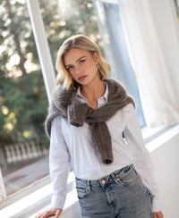 Striped blouse in white and light blue by PLEIN PUBLIQUE, shown by a sunny window.