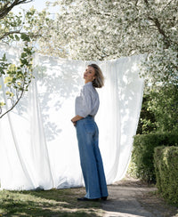 Striped Blouse LA LOIRE White-Black by PLEIN PUBLIQUE, shown surrounded by flowering trees.