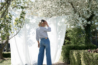 Back view of woman wearing white and black striped PLEIN PUBLIQUE LA LOIRE blouse outdoors.