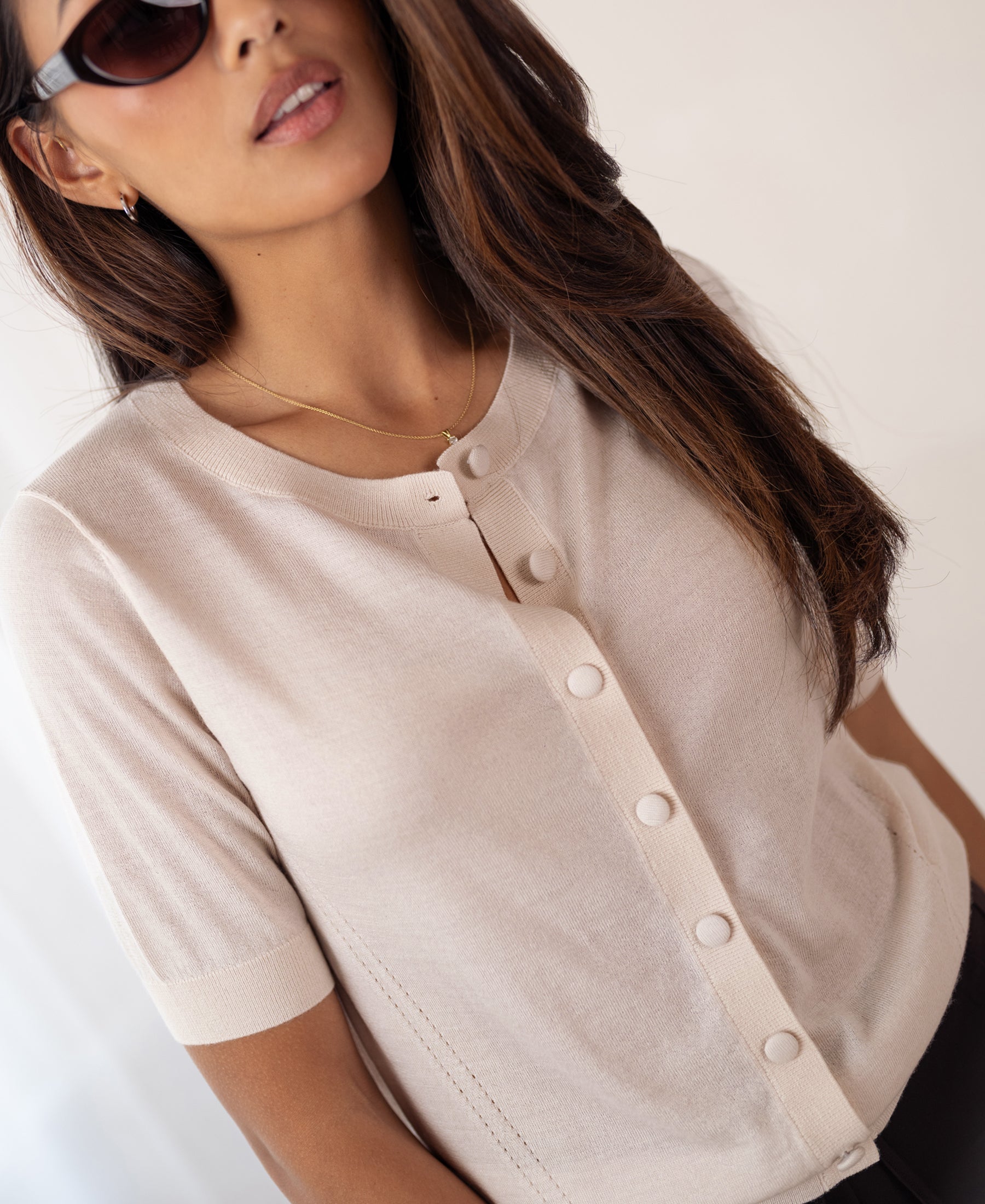 Woman wearing a PLEIN PUBLIQUE merino wool silk cardigan in blush, against a light background.