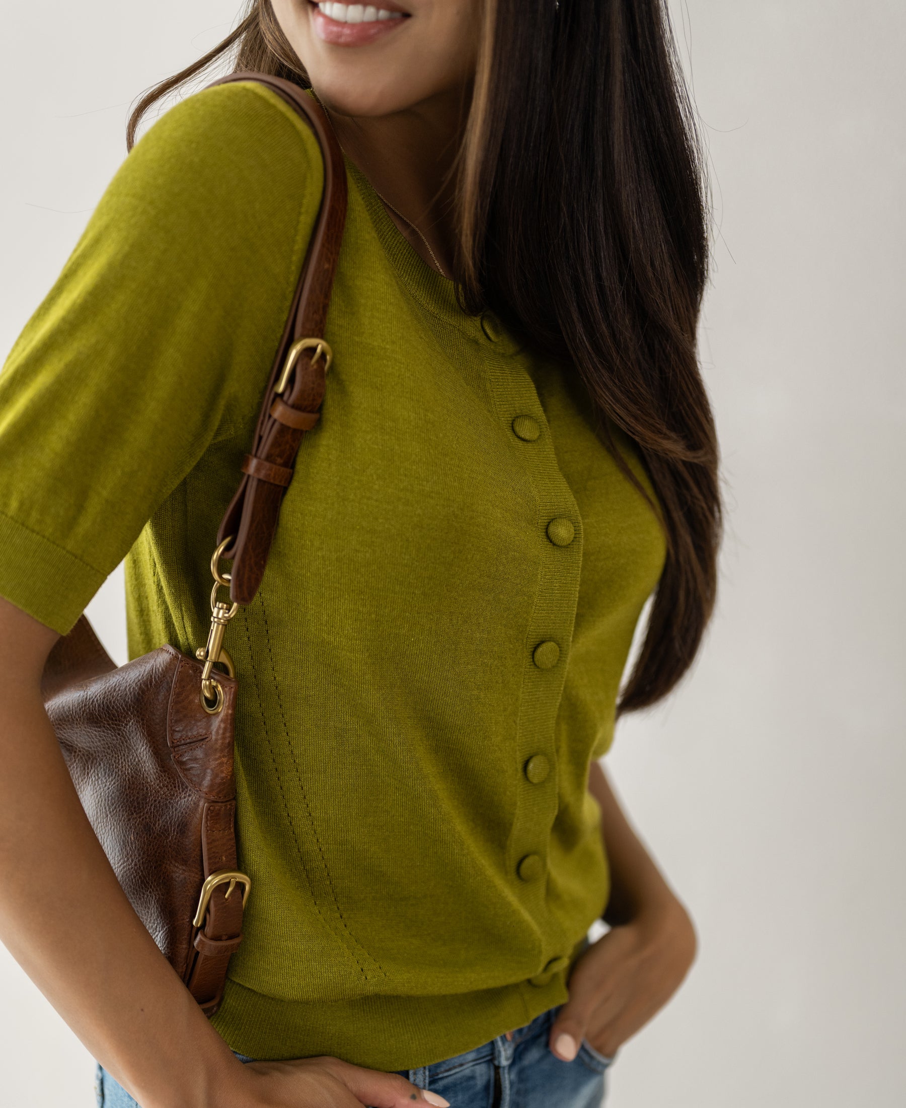 Woman wearing a Merino wool silk cardigan LA LORAINE by PLEIN PUBLIQUE, smiling against a light background.
