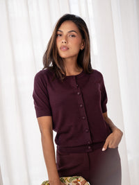 Wine-colored merino wool silk cardigan in front of white curtains.
