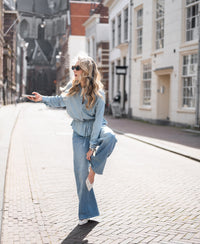 Woman wearing light blue Tencel denim blouse, LA LOZANNE Bleached edition, shown from the front outdoors.