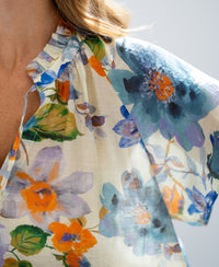 Close-up of light blue floral print blouse top with airy butterfly sleeves by PLEIN PUBLIQUE.