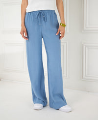 Person wearing LA LYNETTE Jeansblue pants stands indoors.