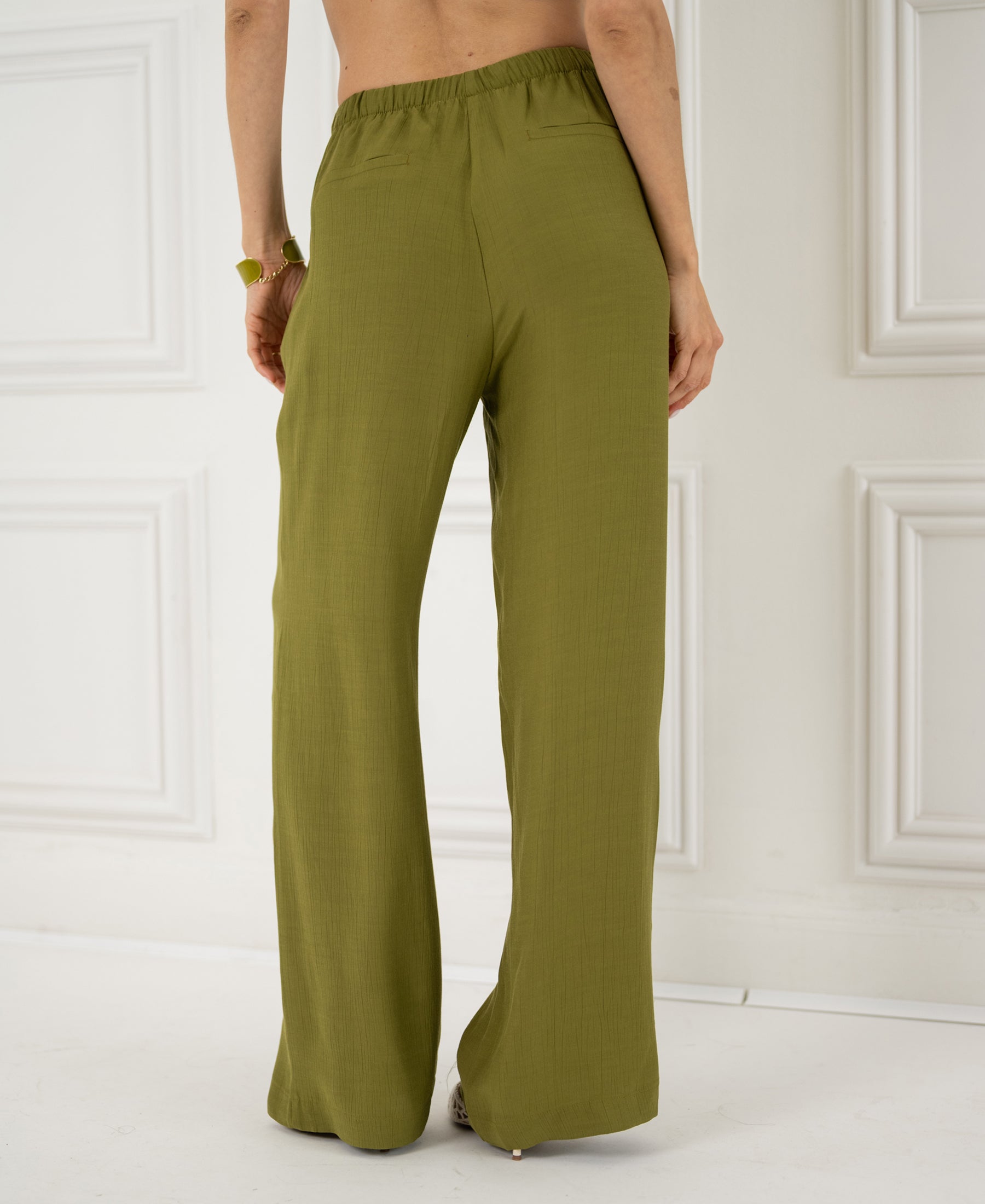 High-waisted, wide-leg olive LA LYNETTE trousers shown from the back indoors.