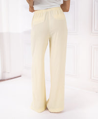 Soft yellow LA LYNETTE pants with elastic waist, shown from the back in a bright white-walled room.